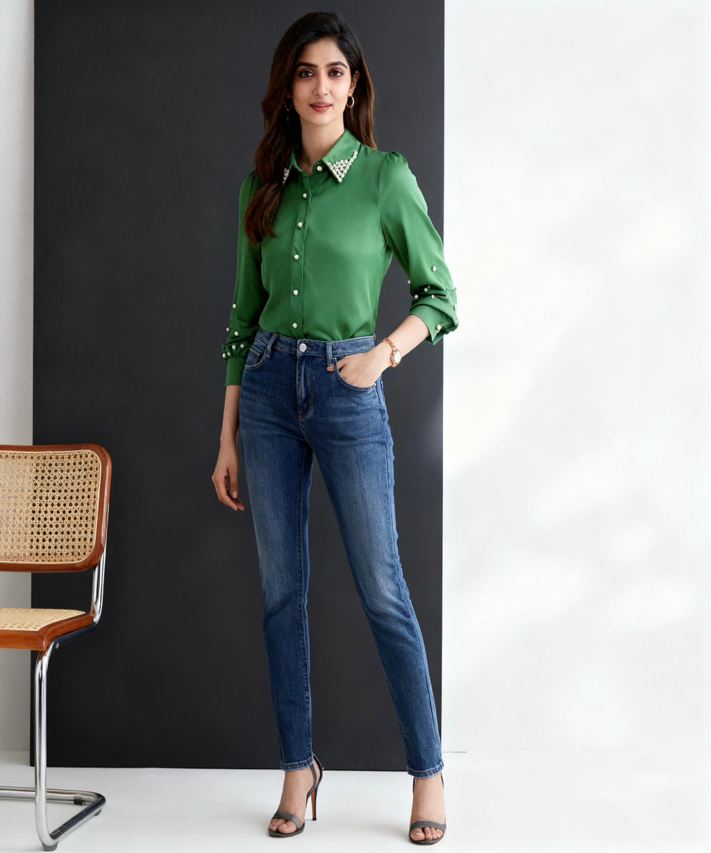 Woman wearing a green shirt and blue jeans standing against a black and white background