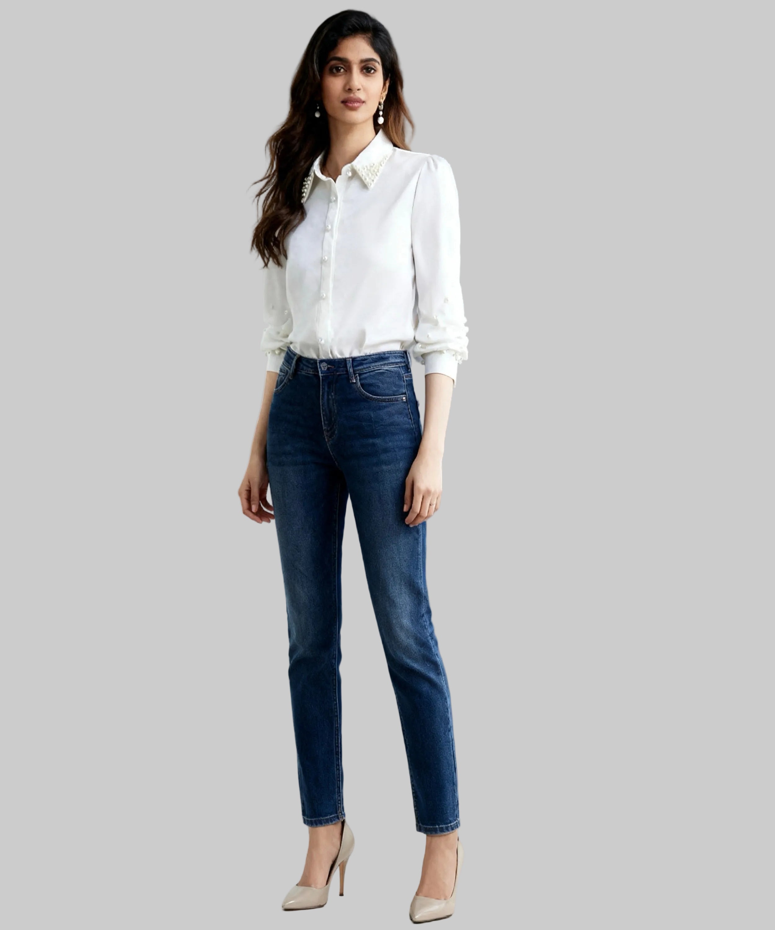 Woman wearing a white shirt and blue jeans against a gray background