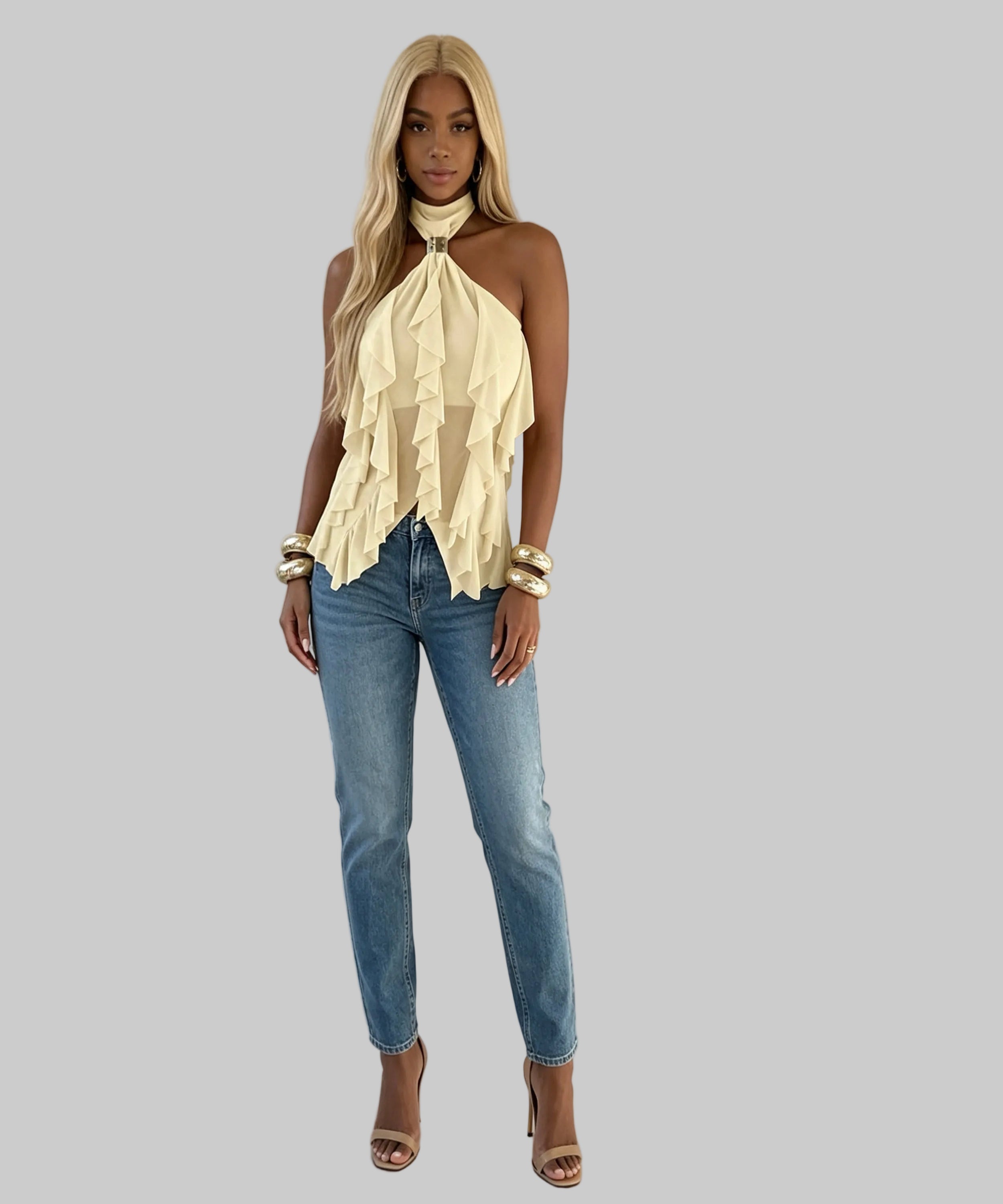Woman wearing a beige halter top and blue jeans against a plain background