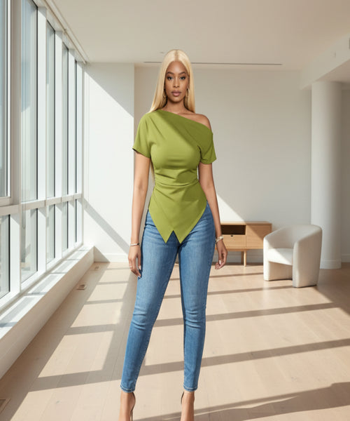 Woman wearing a green top and blue jeans against a gray background