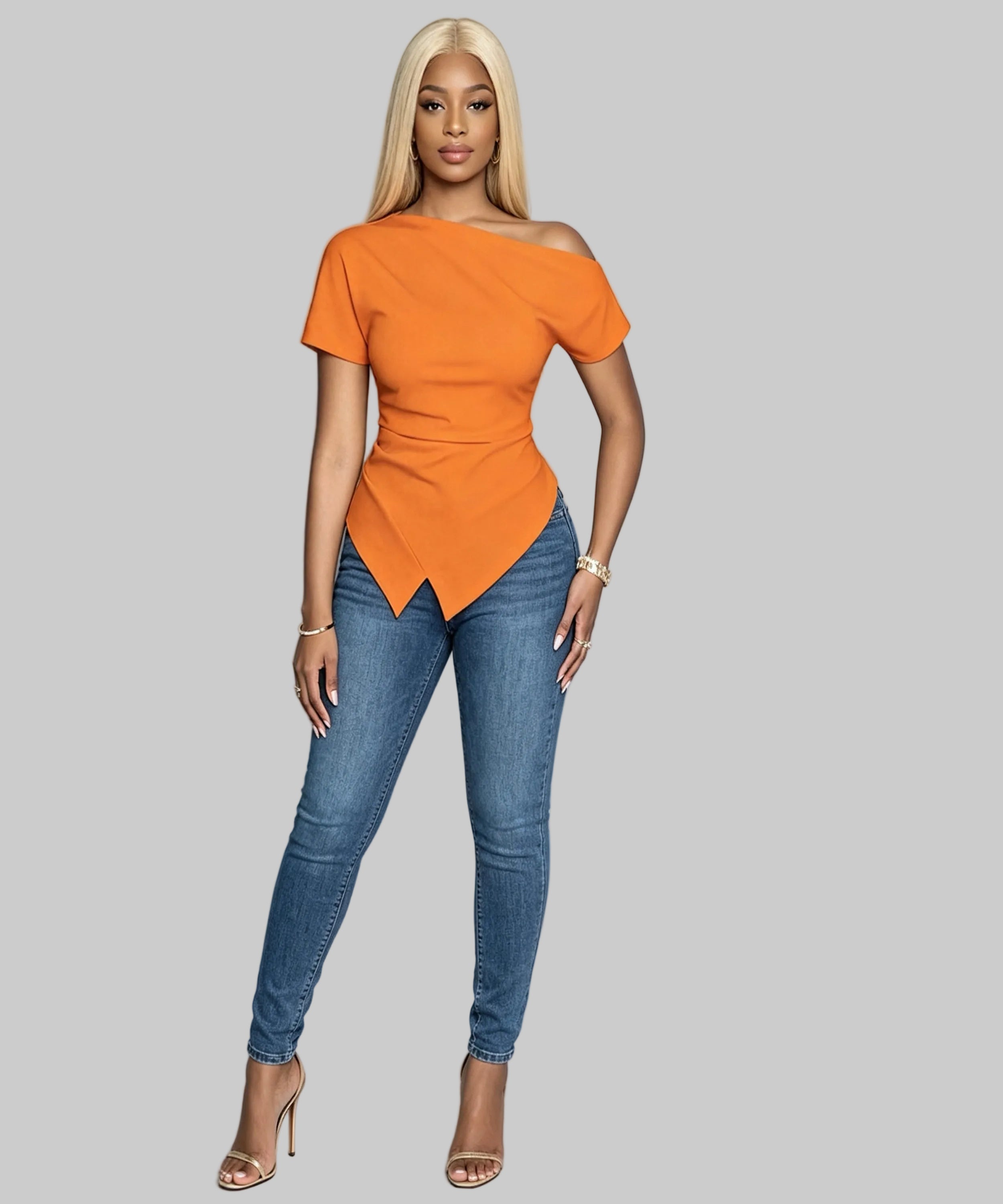 Woman wearing an orange top and blue jeans against a gray background