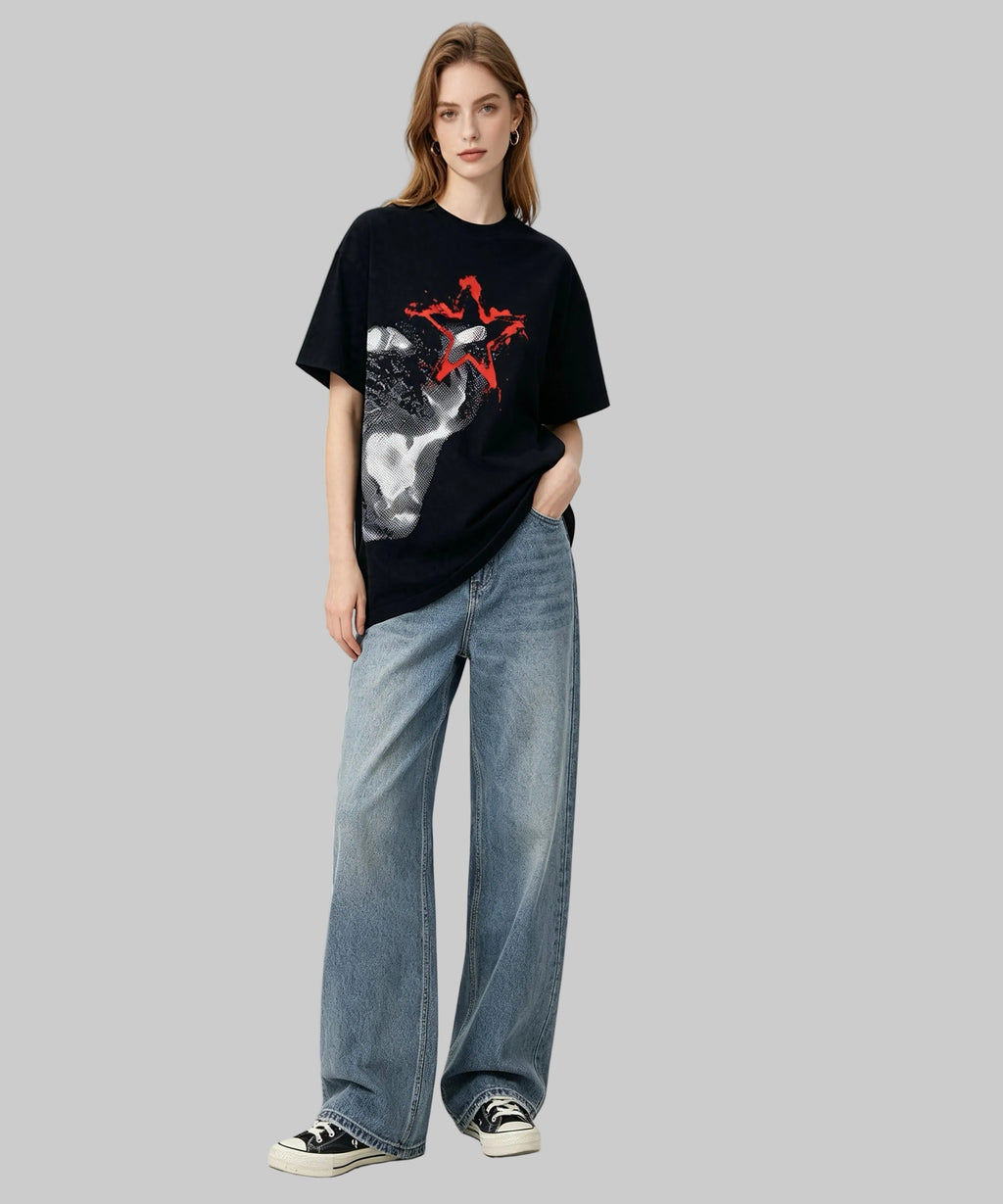 Person wearing a black t-shirt with a graphic design and blue jeans on a white background