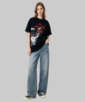 Person wearing a black t-shirt with a graphic design and blue jeans on a white background