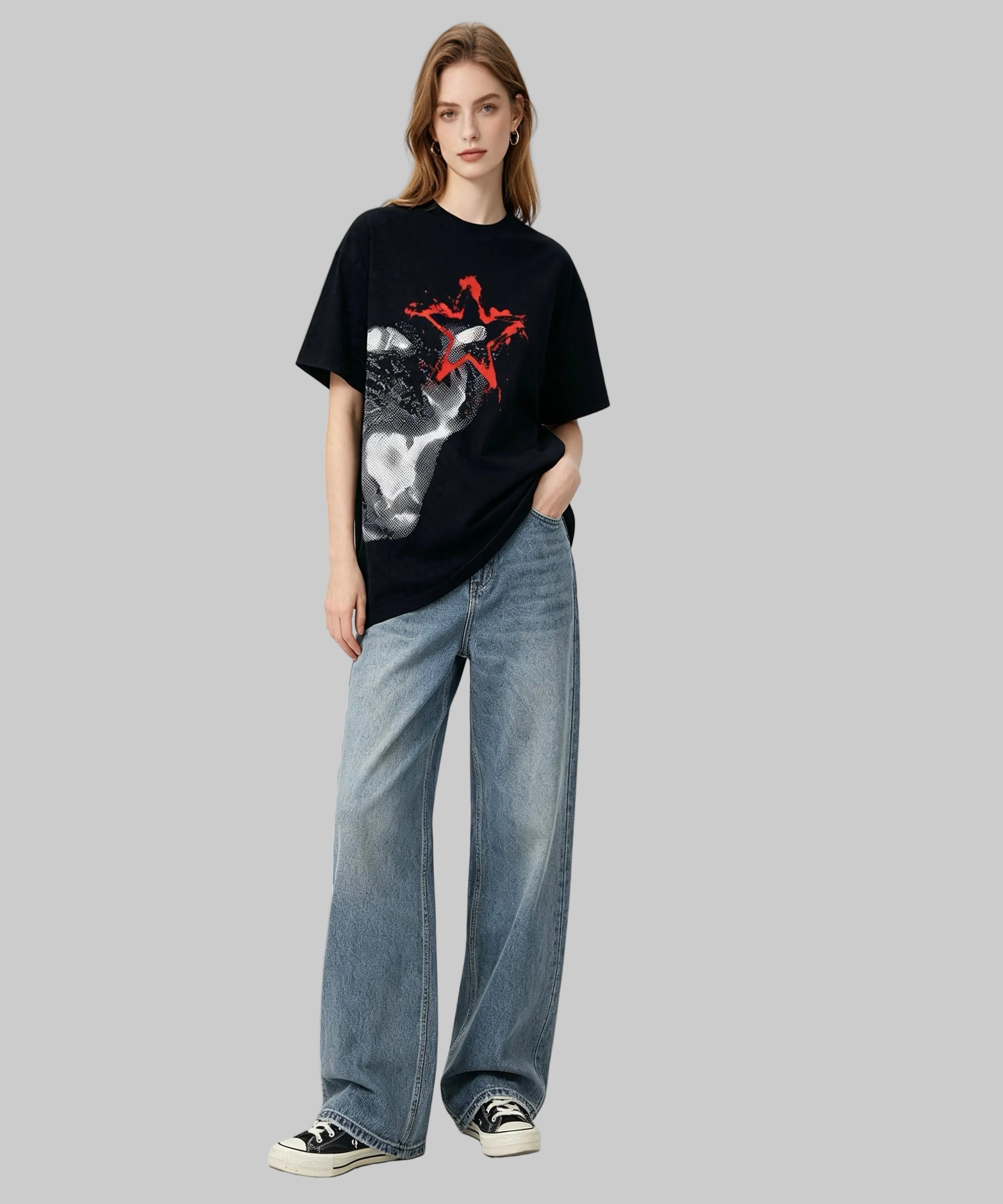 Person wearing a black t-shirt with a graphic design and blue jeans on a white background