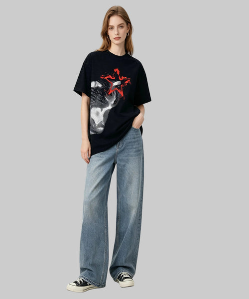 Person wearing a black t-shirt with a graphic design and blue jeans on a white background
