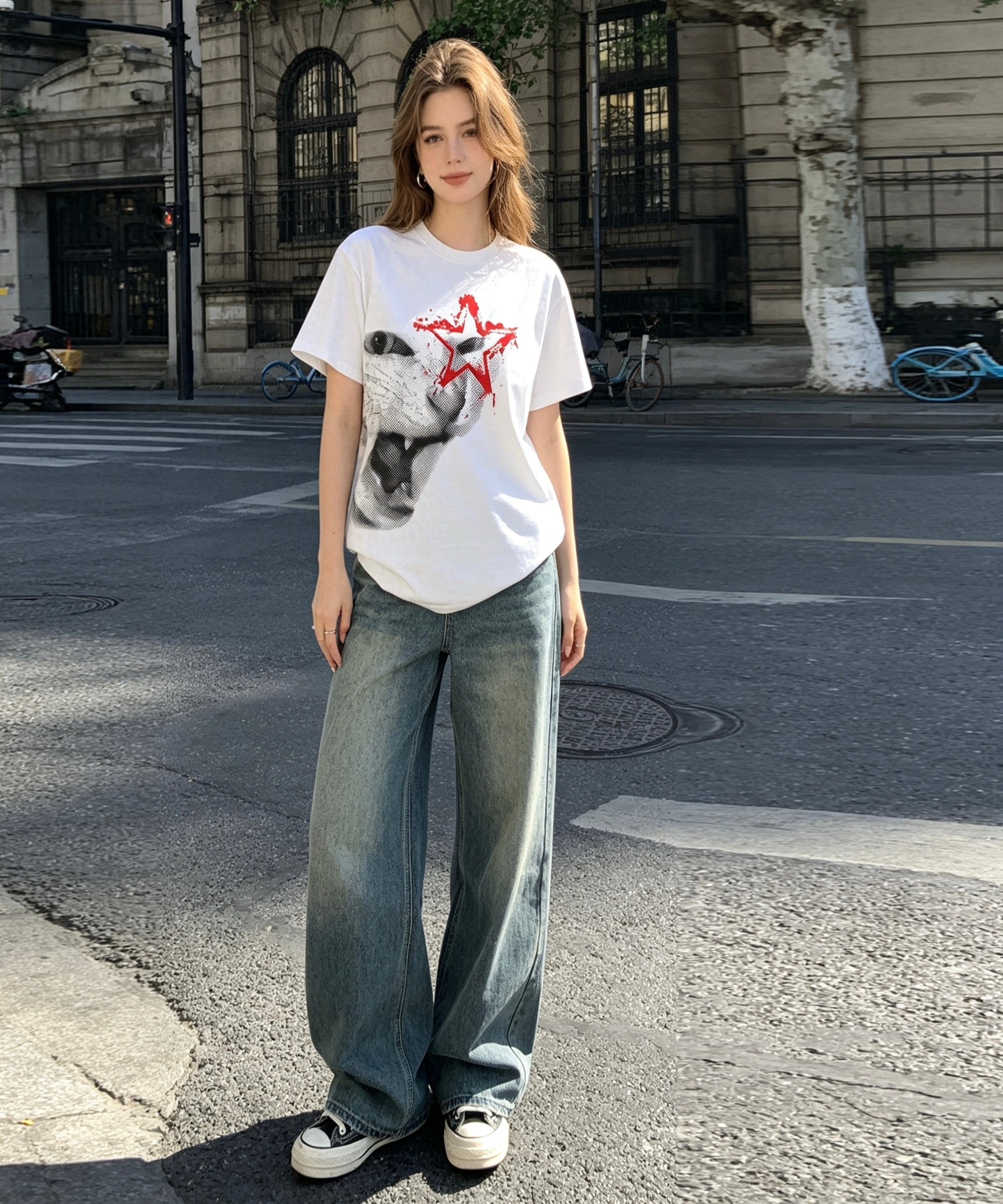 Woman wearing a white t-shirt with a graphic design and blue jeans standing on a street.