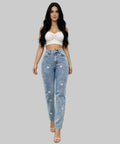 Woman wearing a white crop top and blue jeans with heart patterns on a patio.