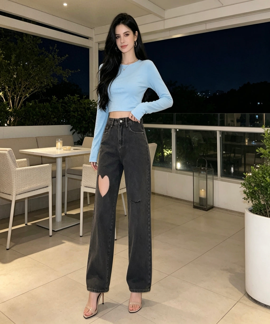 Woman in light blue top and black jeans standing on a patio at night.
