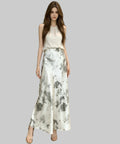 Woman wearing a white top and floral skirt standing on a white background.