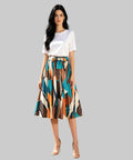 Woman in a colorful skirt and white top standing on a white background