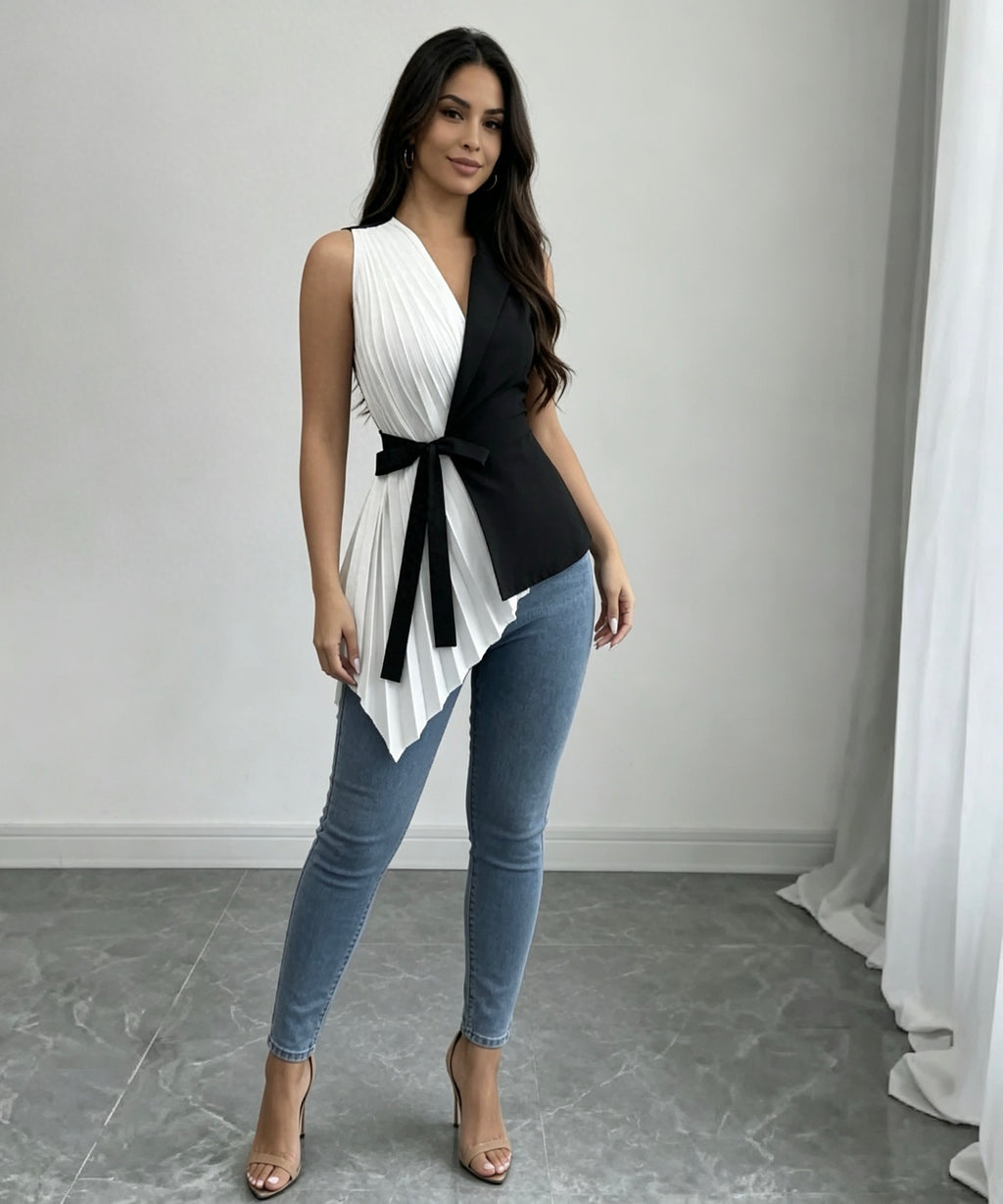 Woman wearing a black and white sleeveless top with blue jeans in a minimalistic setting.