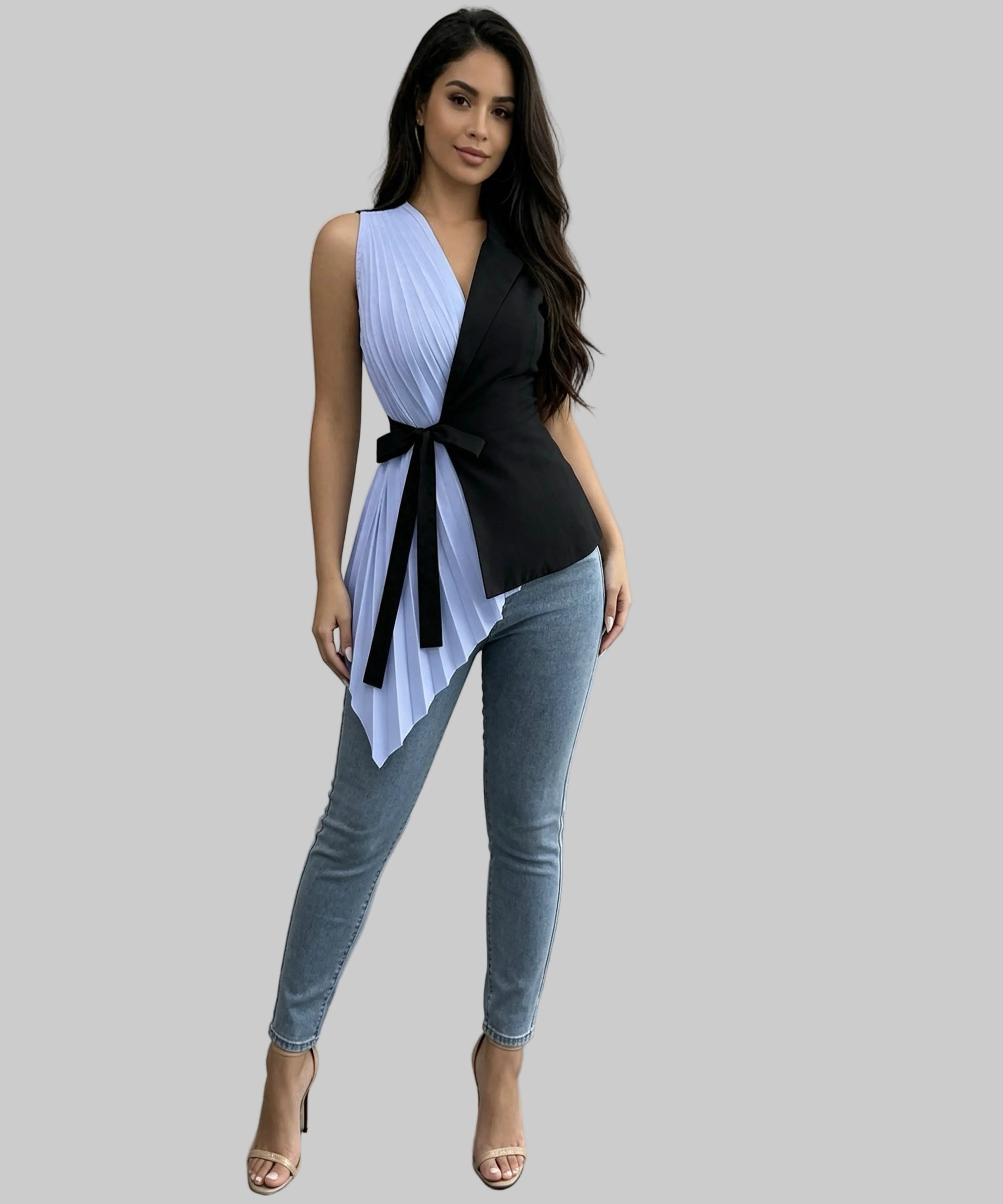Woman wearing a black and white sleeveless top with a belt and blue jeans in a room.