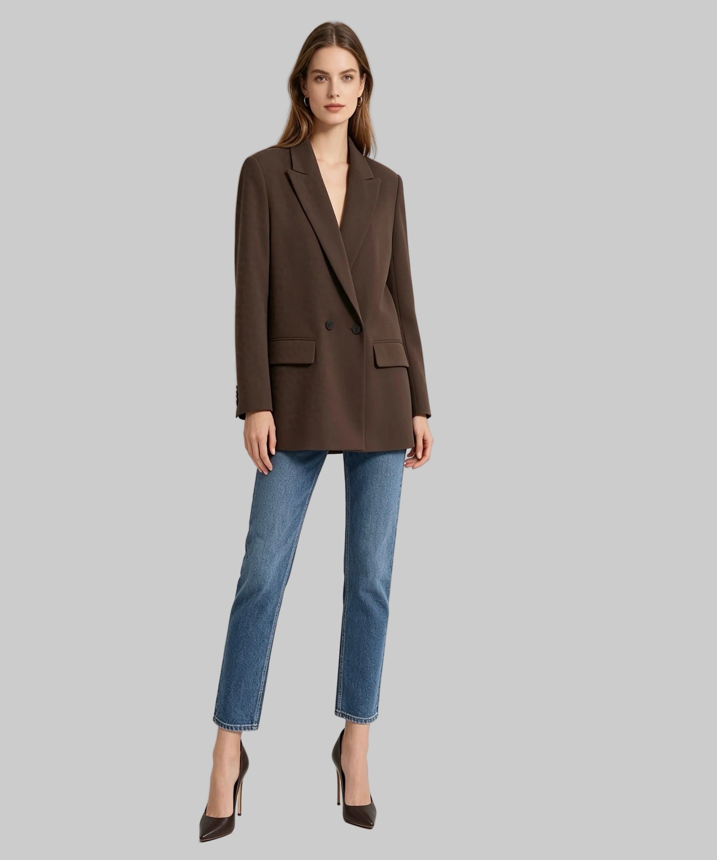 Woman wearing a brown blazer and blue jeans on a white background