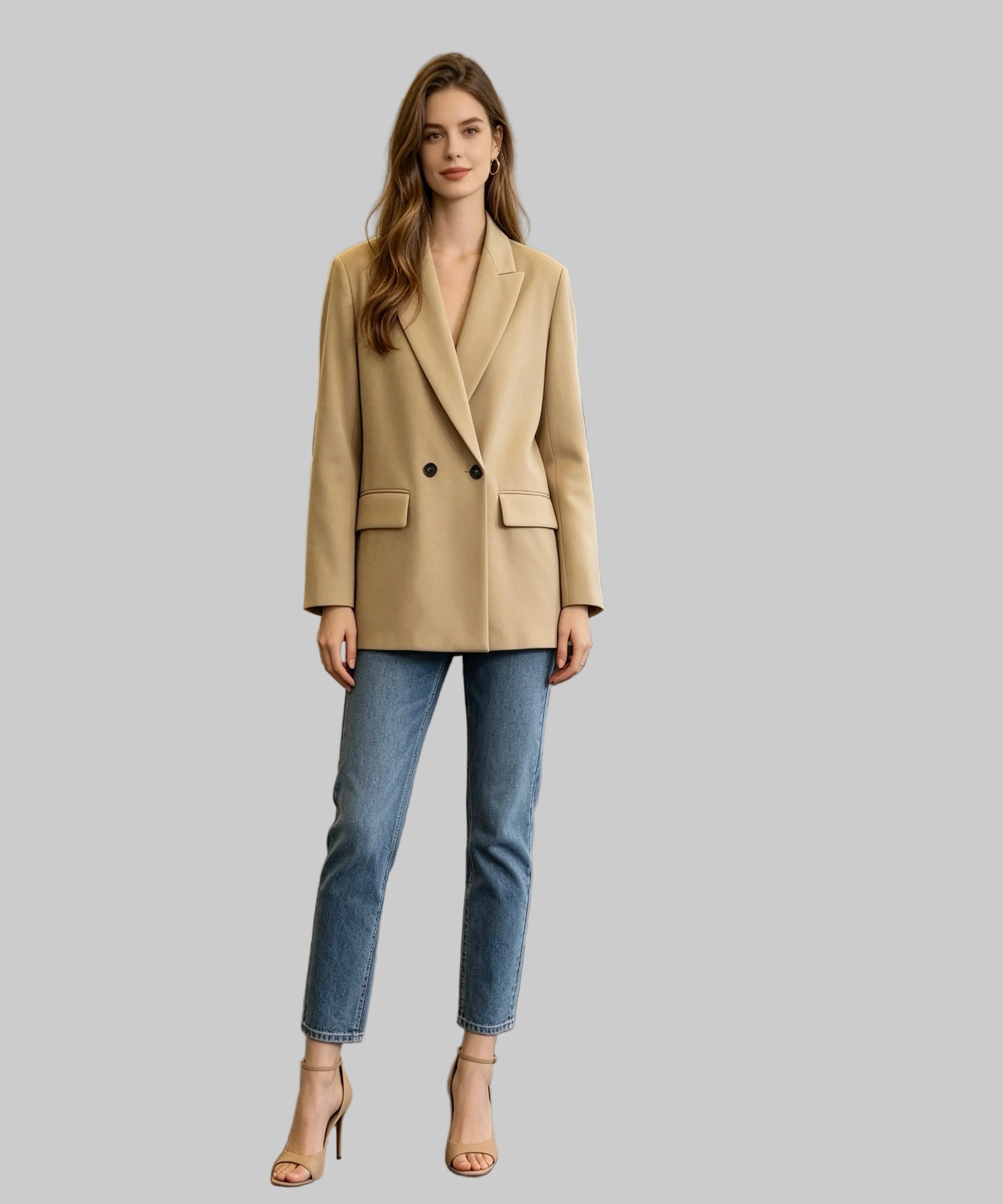 Woman in a beige blazer and blue jeans standing in an office setting