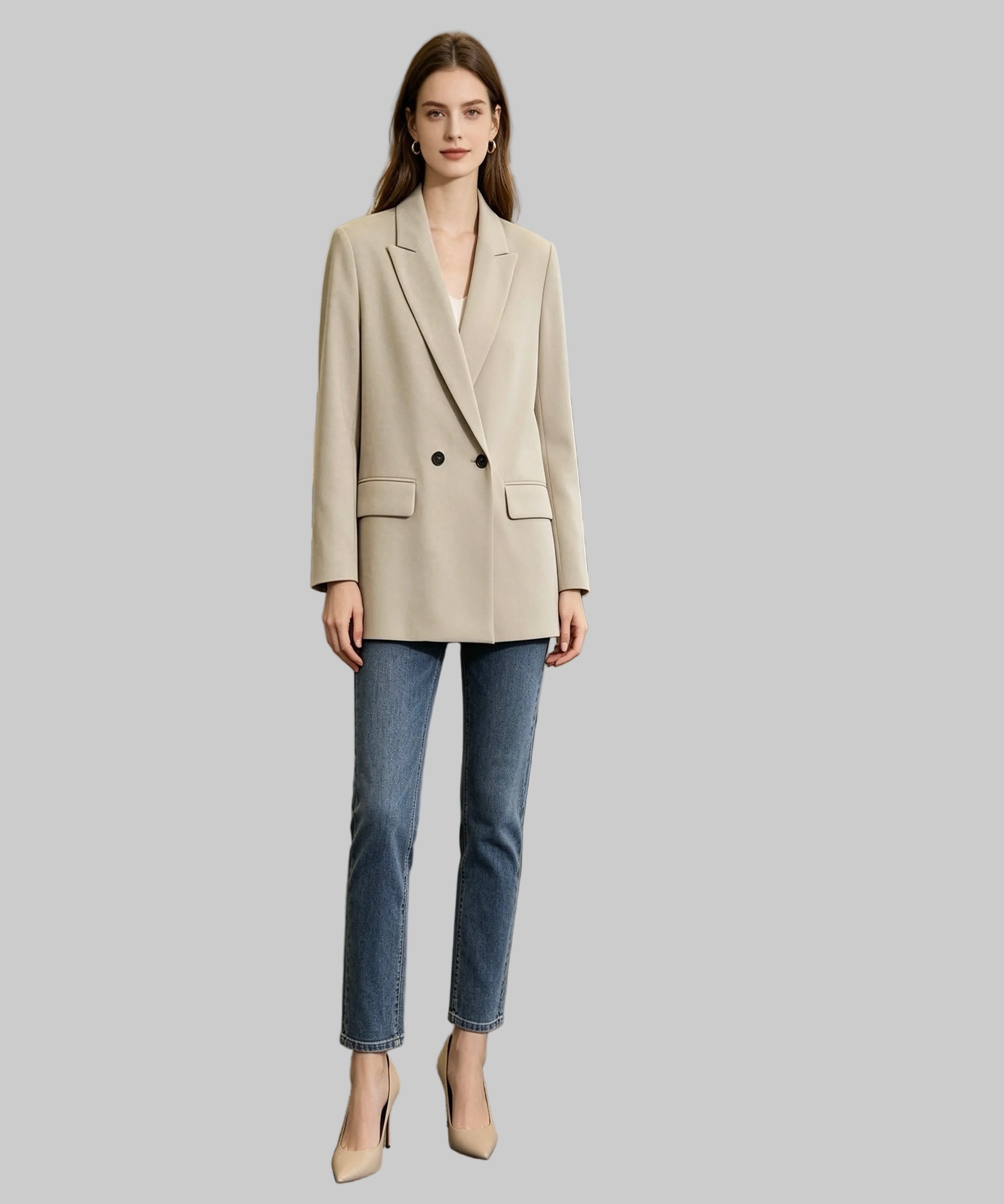 Woman in a beige blazer and blue jeans standing in an office setting