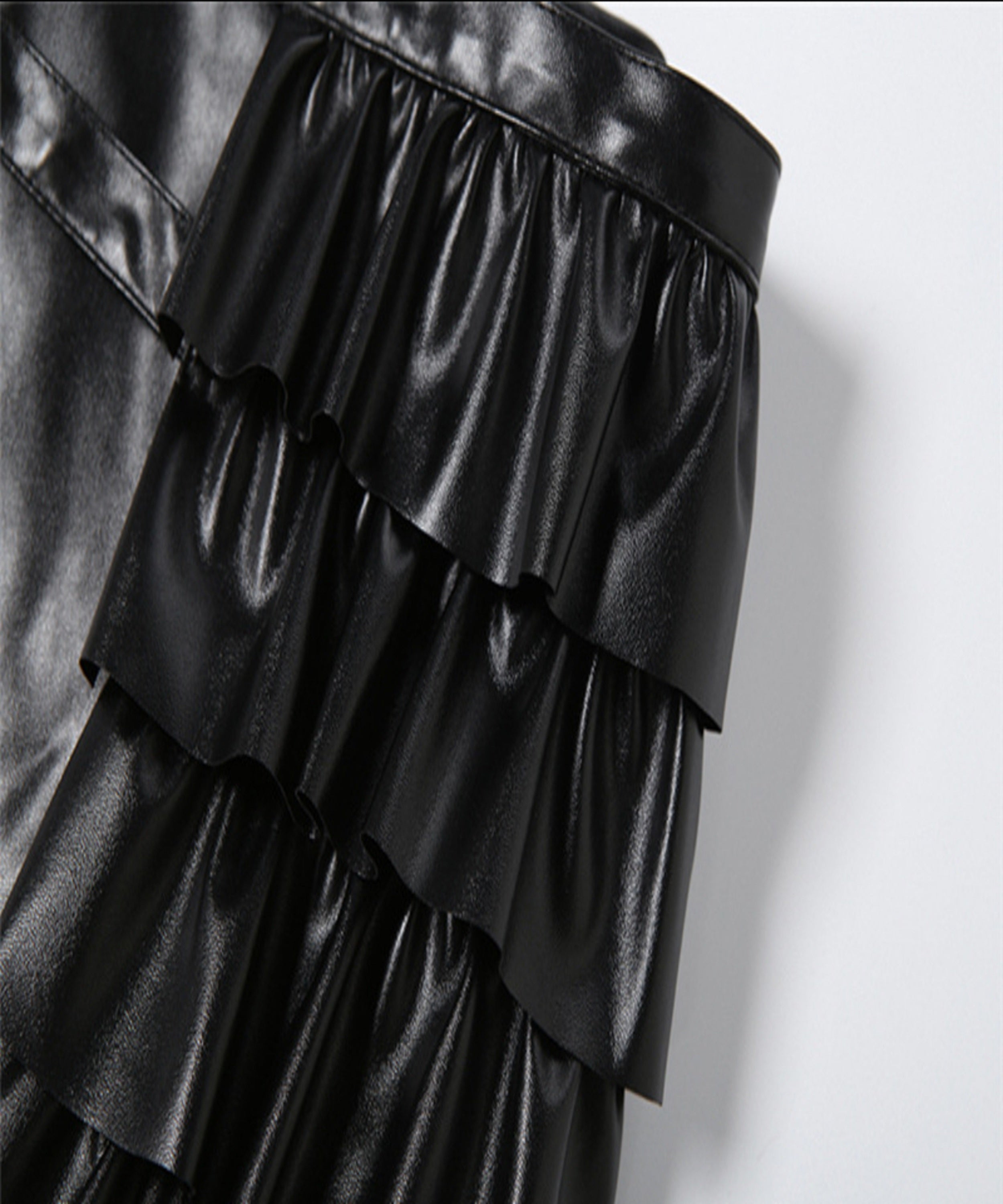 Black leather ruffled skirt on a light gray background