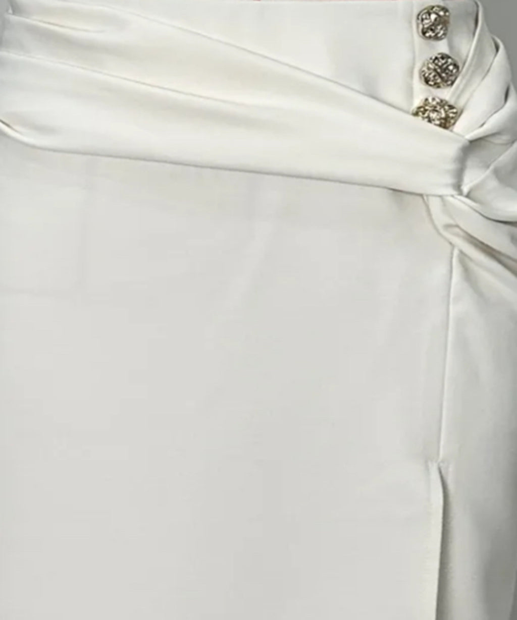 Close-up of a white dress with decorative buttons on a plain background