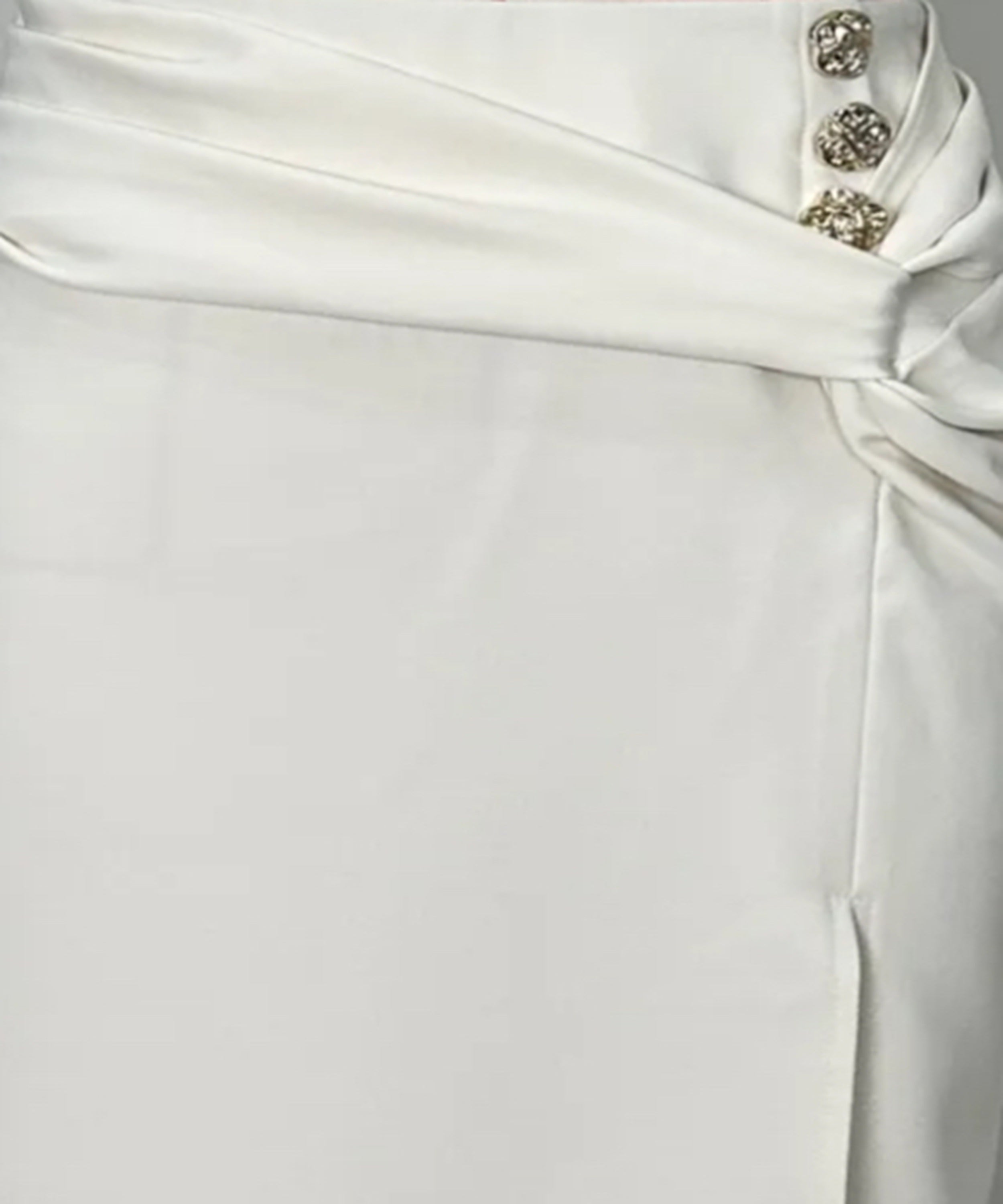 Close-up of a white dress with decorative buttons on a plain background