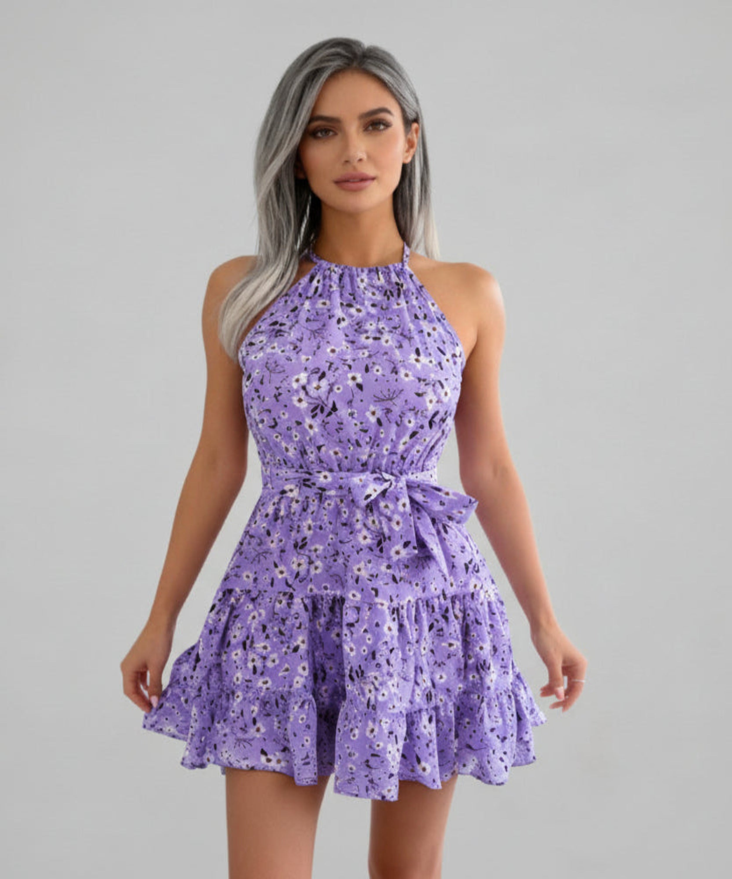 Woman wearing a purple floral dress on a light grey background
