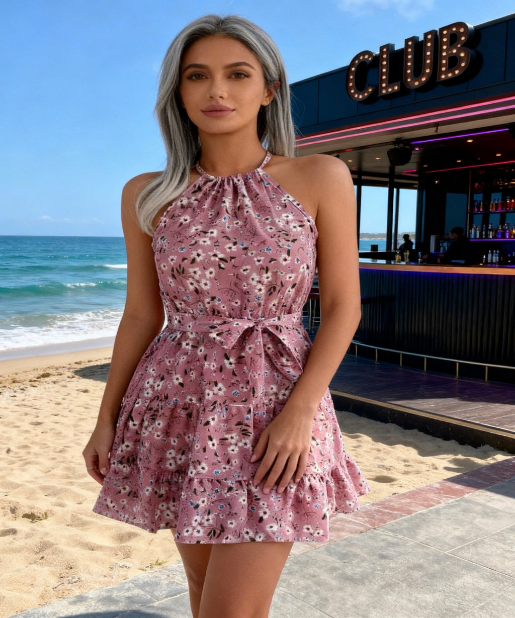 Woman in a floral dress standing on a beach with a club in the background