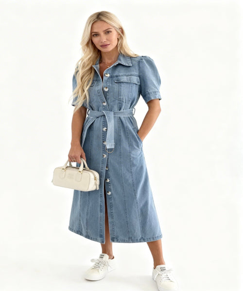 Woman wearing a denim dress holding a white handbag on a white background