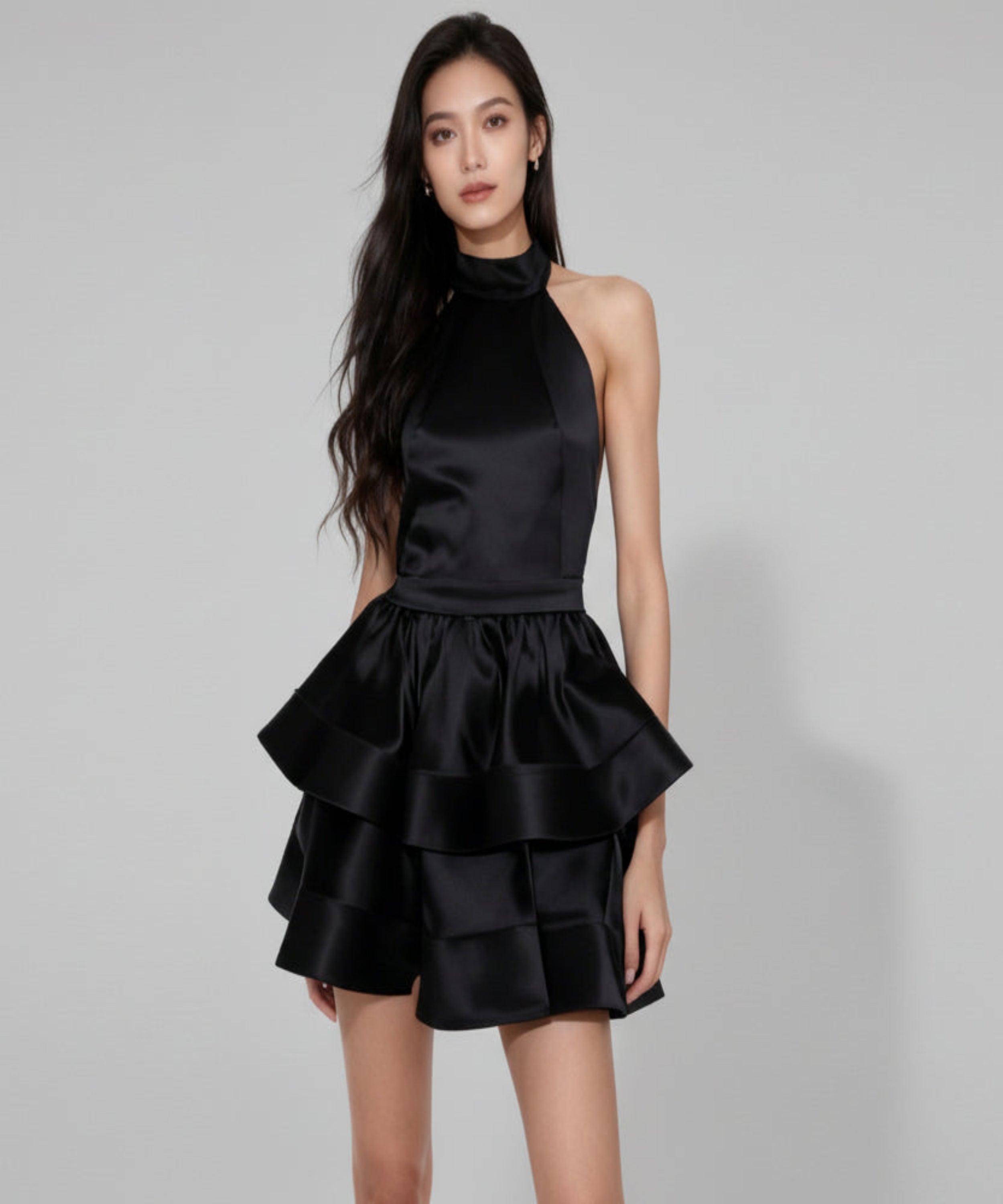 Black ruffled dress worn by a model on a white background