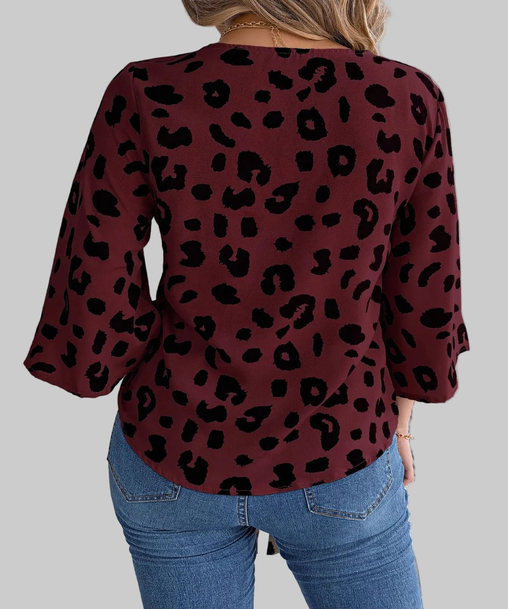 Person wearing a burgundy leopard print top and blue jeans on a white background