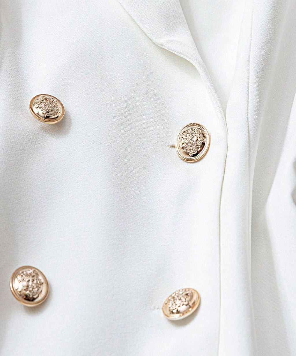 Close-up of a white coat with gold buttons on a light gray background