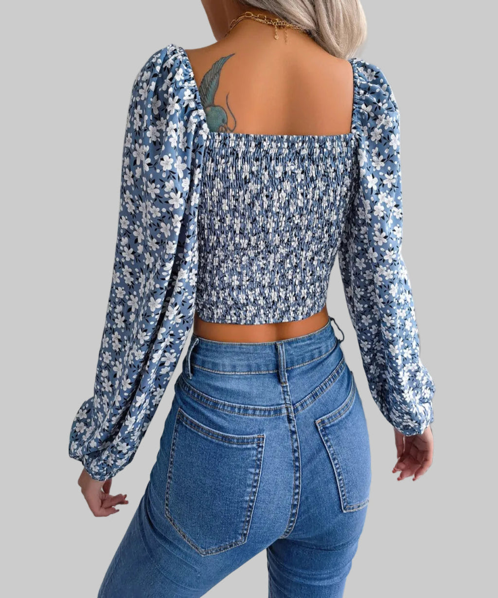 Person wearing a blue floral top and jeans with a white background