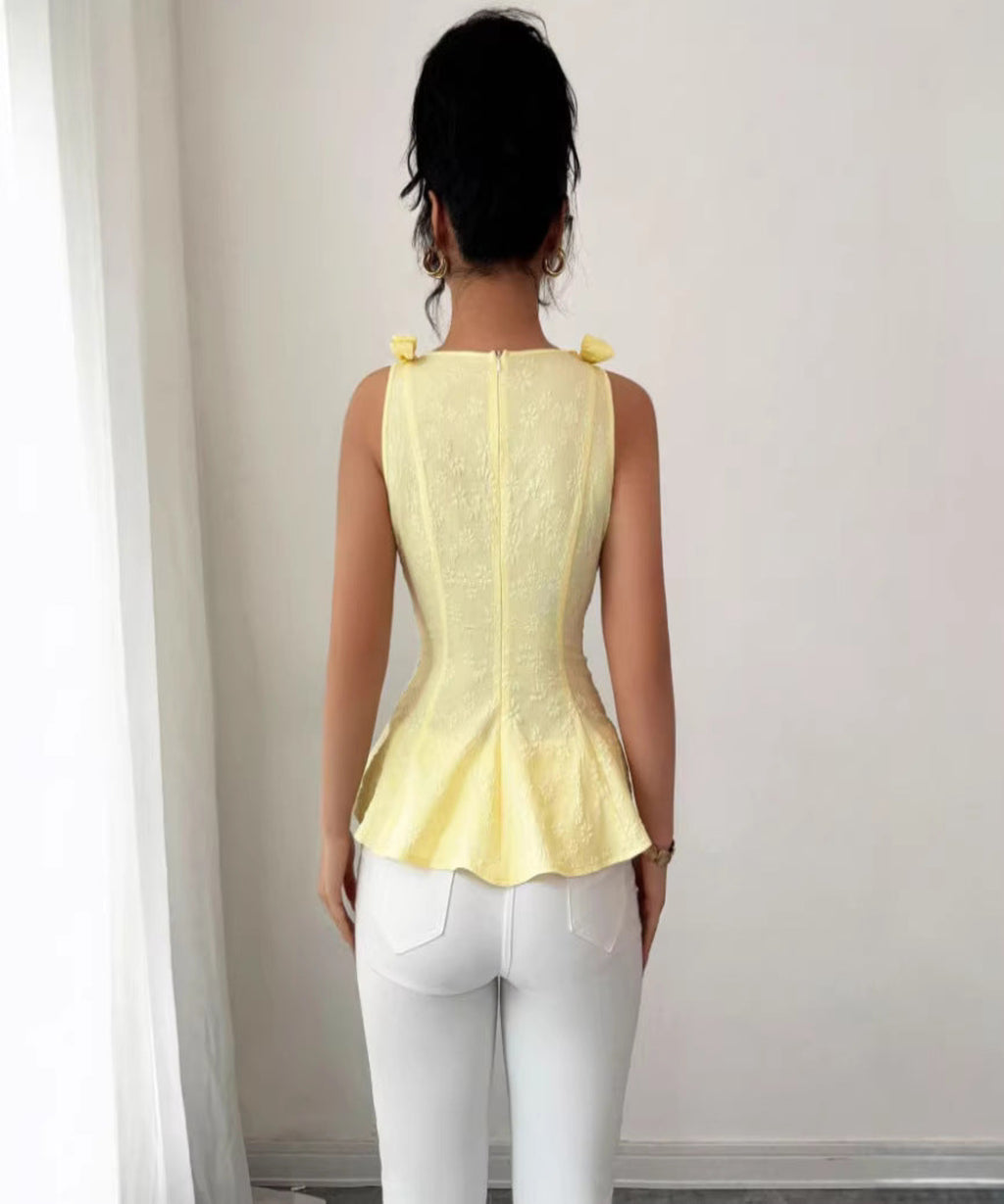 Person wearing a yellow top and white pants against a plain background