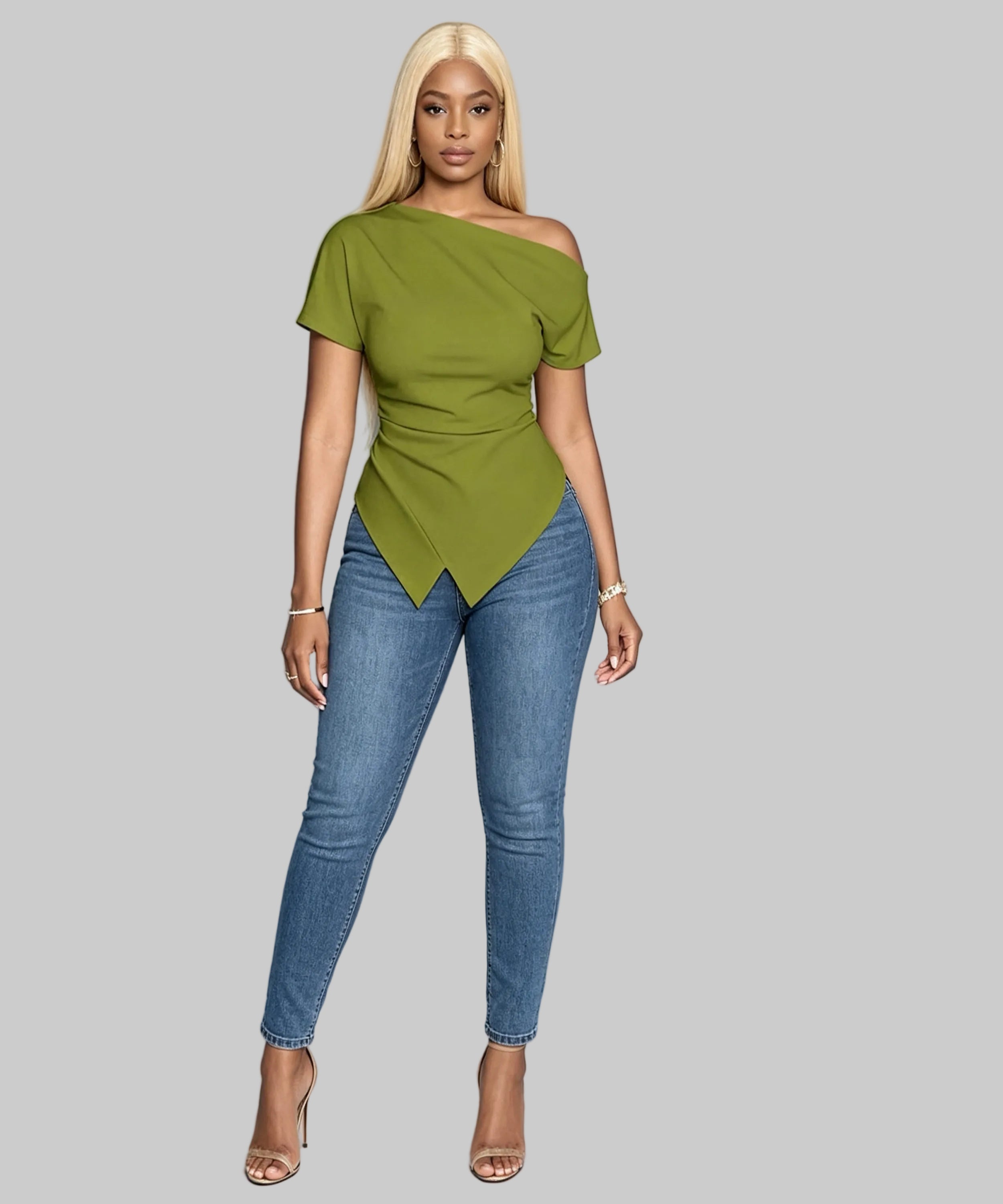 Woman wearing a green top and blue jeans against a light gray background